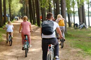 A group of cyclists with backpacks ride bicycles on a forest road enjoying nature photo