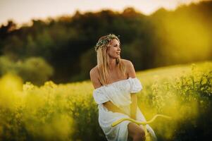 a woman enjoys a bike ride in a field full of bright yellow rapeseed photo