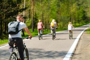 A group of cyclists with backpacks ride bicycles on a forest road enjoying nature photo