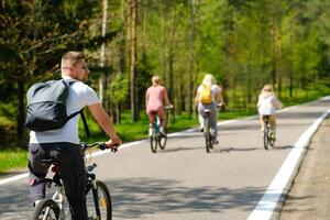 A group of cyclists with backpacks ride bicycles on a forest road enjoying nature photo
