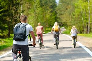 A group of cyclists with backpacks ride bicycles on a forest road enjoying nature photo