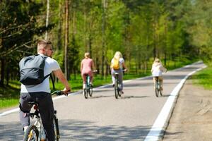 A group of cyclists with backpacks ride bicycles on a forest road enjoying nature photo