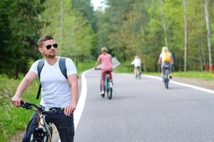 A group of cyclists with backpacks ride bicycles on a forest road enjoying nature photo