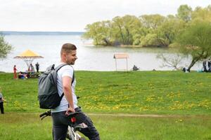 A cyclist with a backpack is standing on a bicycle in a clearing enjoying nature photo