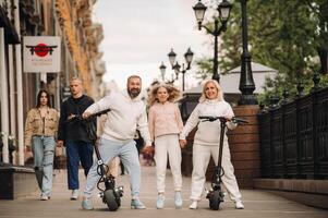 A family in white clothes stands in the city on electric scooters photo