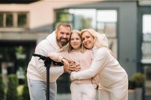 A family in white clothes stands in the city on electric scooters photo