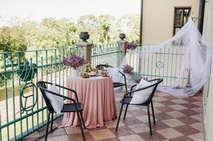 Delicate morning tea table setting with lilac flowers in Nesvizh castle, antique spoons and dishes on the table with a pink tablecloth photo