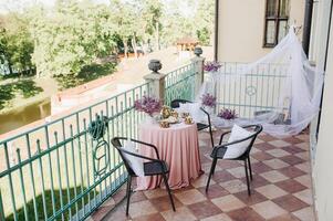 Delicate morning tea table setting with lilac flowers in Nesvizh castle, antique spoons and dishes on the table with a pink tablecloth photo