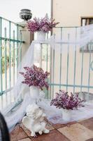 Delicate morning tea table setting with lilac flowers in Nesvizh castle, antique spoons and dishes on the table with a pink tablecloth photo