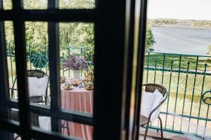 Delicate morning tea table setting with lilac flowers in Nesvizh castle, antique spoons and dishes on the table with a pink tablecloth photo