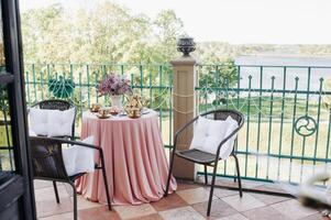 Delicate morning tea table setting with lilac flowers in Nesvizh castle, antique spoons and dishes on the table with a pink tablecloth photo