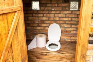 A simple village toilet with a huge roll of toilet paper.Large roll of toilet paper in the toilet photo
