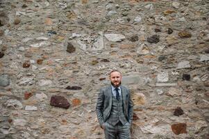 A man with a beard in a strict grey three-piece suit with a tie in the old town of Sirmione, a Stylish man in a grey suit in Italy photo