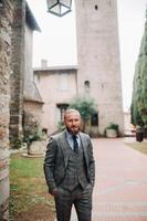 A man with a beard in a strict grey three-piece suit with a tie in the old town of Sirmione, a Stylish man in a grey suit in Italy photo