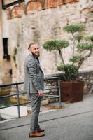 A man with a beard in a strict grey three-piece suit with a tie in the old town of Sirmione, a Stylish man in a grey suit in Italy photo