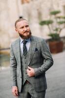 A man with a beard in a strict grey three-piece suit with a tie in the old town of Sirmione, a Stylish man in a grey suit in Italy photo
