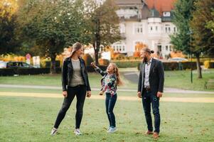 A happy family of three runs through the grass in Austria's old town.A family walks through a small town in Austria.Europe.Velden am werten Zee photo