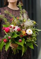 A large bouquet of mixed flowers in the hands of a woman. The work of a florist in a flower shop photo