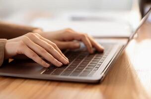 Working At Laptop Pc. Close up image of female hands typing text or programming code using computer at home photo