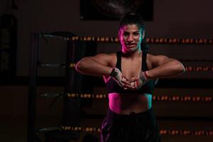 female Latina boxer with her hands bandaged working out at a training session at a gym throwing a punch photo
