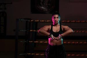 female Latina boxer with her hands bandaged working out at a training session at a gym throwing a punch photo