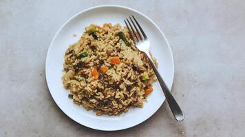 Plate of fried rice with vegetables and meat, fork placed centrally, simple presentation top view Copy Space video