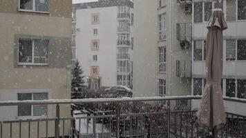 A heavy snowfall transforms the urban landscape into a winter wonderland. Fluffy flakes drift gently onto balconies and rooftops, creating a serene atmosphere in the city. video