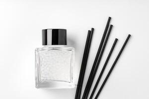 A minimalist display of essential oil and black diffuser sticks on a clean white background photo