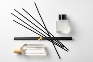 A minimalist display of essential oil and black diffuser sticks on a clean white background photo