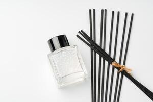 A minimalist display of essential oil and black diffuser sticks on a clean white background photo