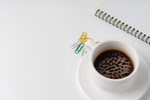 Cup of coffee and notepad on white background photo