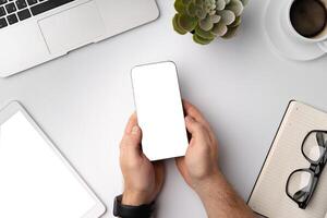 Man using blank smartphone on workplace desk, top view photo