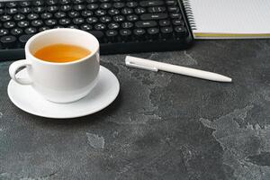 Office desk with computer keyboard, notepad and pen photo