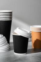 Stack of coffee cups in various colors with lids on a gray surface photo