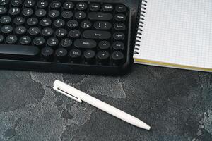 Office desk with computer keyboard, notepad and pen photo