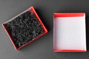 Open red paper box with tinsel on black background photo