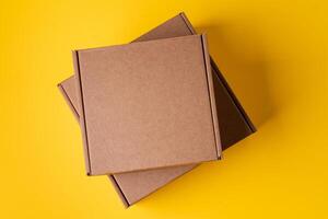 Beige cardboard boxes on yellow background, close up photo