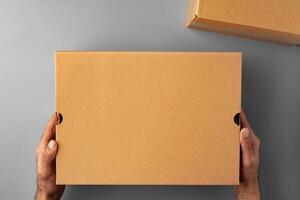 Parcel cardboard box in a man hands on a gray table background photo