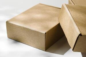 Three brown cardboard boxes arranged on a light surface with soft shadows photo