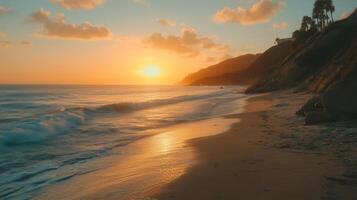 Golden sunset over calm waves at a coastal beach with cliffs and palm trees in the background on a serene evening photo
