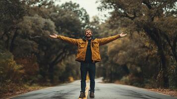 A joyful man stands with open arms in the middle of a serene, tree-lined road during a calm autumn day photo