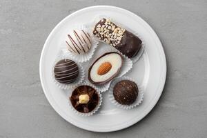 Chocolate candies in a white plate on gray background photo