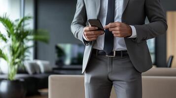 Business professional in a sleek modern office checking messages on a smartphone during a busy workday in the afternoon photo
