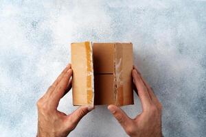 Parcel cardboard box in a man hands on a gray table background photo