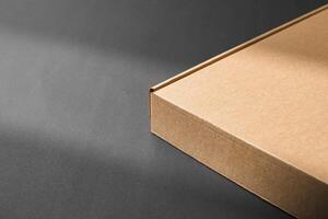 A cardboard box casting shadows on a dark surface in a striped light pattern photo