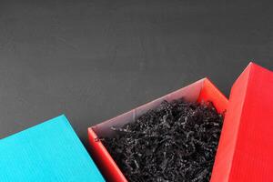 Open red paper box with tinsel on black background photo