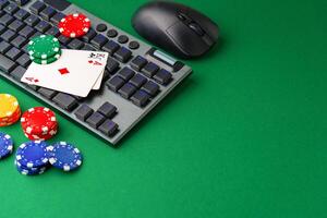 Chips and playing cards on a green felt surface near a computer keyboard photo