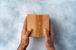 Parcel cardboard box in a man hands on a gray table background photo