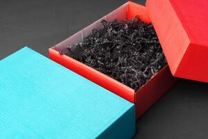 Open red paper box with tinsel on black background photo