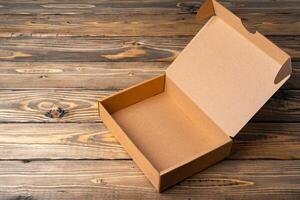 One open cardboard box on wooden background photo
